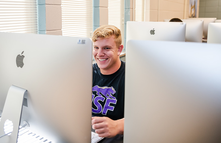 USF student working on his computer during a graphic design class.