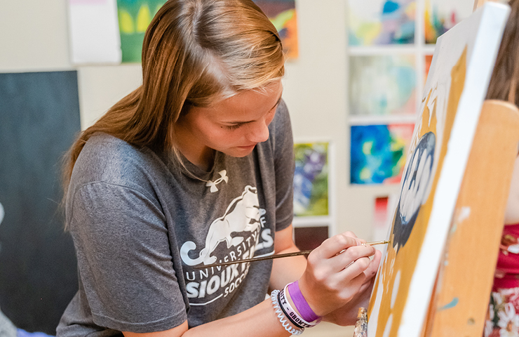 Art student painting on a canvas during class.