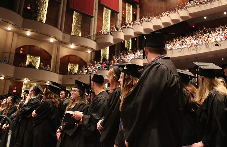 Several students dressed in graduation cap and gown at ceremony.